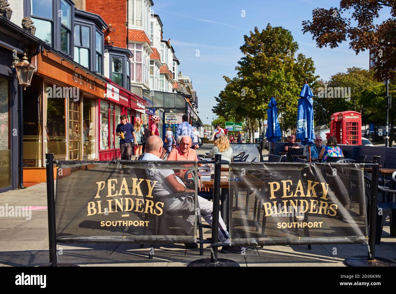 Zwei Männer sitzen vor dem Peaky Blinders Pub auf dem Haupteinkaufsstraße in Southport Stockfoto