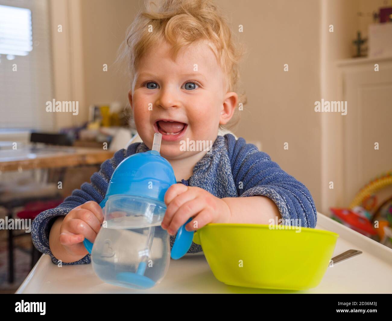 Glücklicher ein Jahr alter Junge, der beim Essen Wasser trinkt Stockfoto