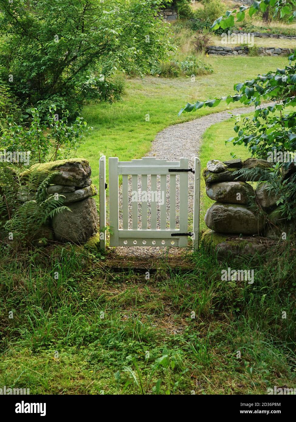 Eingang zum grünen Garten mit weißem Tor Stockfoto