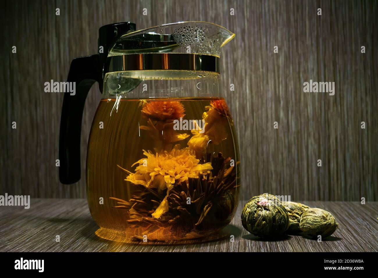 Blühende Teeblume in Glas Teekanne auf braunem Holzhintergrund Stockfoto