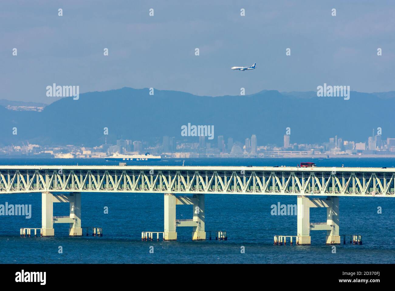 Osaka / Japan - 16. November 2017: ANA-Flugzeug fliegt über die Sky Gate Bridge und landet auf dem Kansai International Airport mit der Stadt Kobe visib Stockfoto