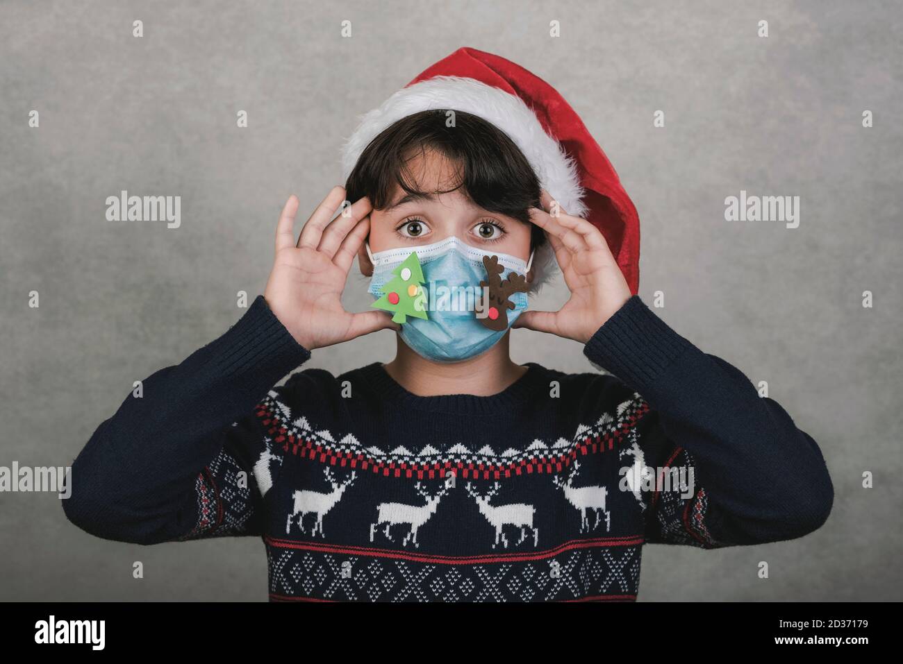 Frohe Weihnachten, Kind mit lustigen weihnachten medizinische Maske auf grauem Hintergrund Stockfoto