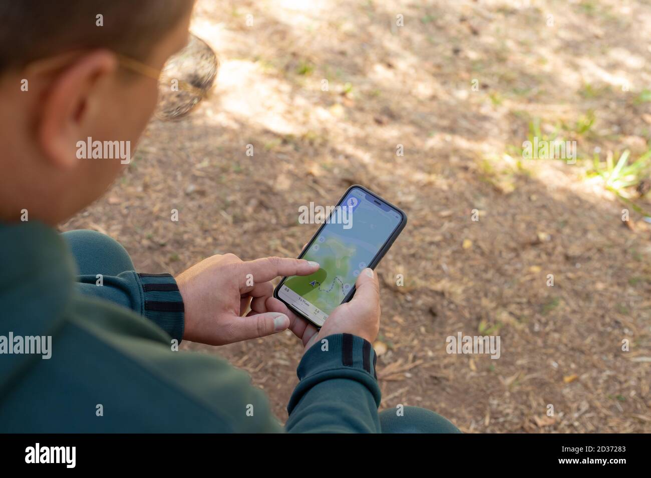 Mann mit einem Smartphone mit einer Online-Karte auf der Suche nach dem richtigen Weg im Wald. Stockfoto