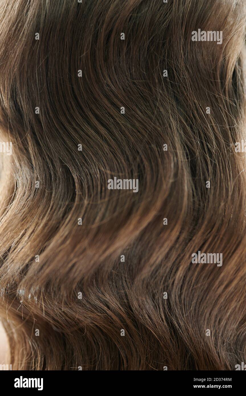 Brunette Haare Hintergrund. Lange lockige Haarstruktur Stockfoto
