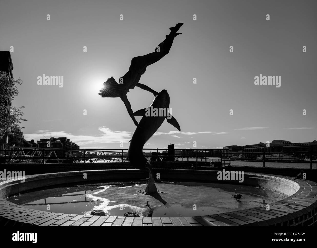 Londons Brunnen - Mädchen mit einem Delphin und aufgehender Sonne dahinter, schwarz-weiß Foto Stockfoto