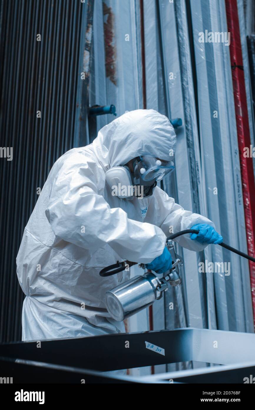 Vertikale Aufnahme einer Person in schützenden Overall Anzug und Spritzlackierung der Gasschutzmaske Stockfoto