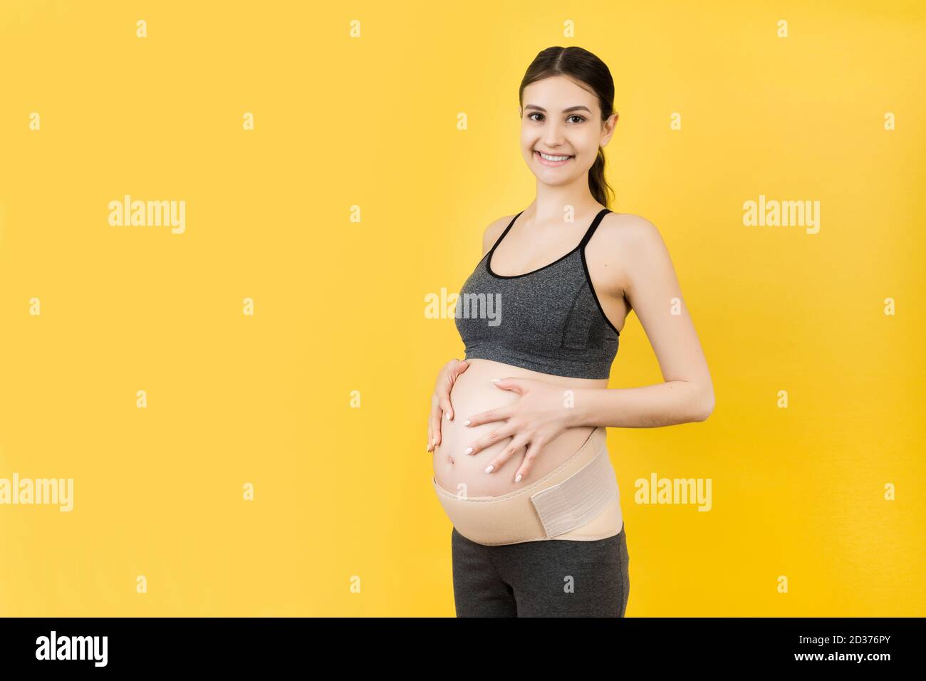 Portrait einer schwangeren Frau mit Schwangerschaftskorsett gegen  Rückenschmerzen auf gelbem Hintergrund mit Kopierraum. Orthopädische  Bauchstützgurt Konzept Stockfotografie - Alamy