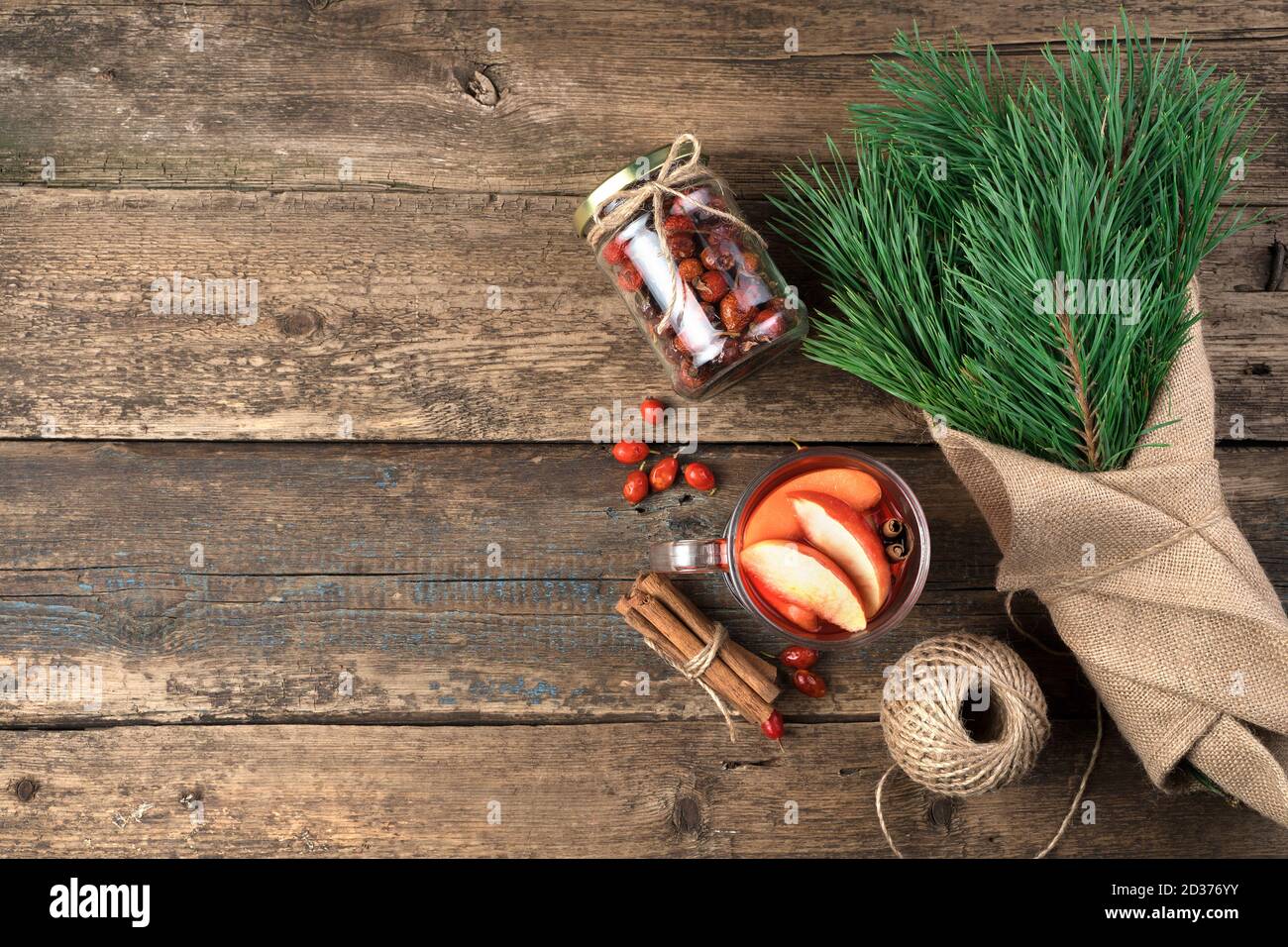 Weihnachts-Geschenkset: Ein Bouquet mit Kiefernzweigen, ein Glas Glühwein mit Zimt und Beeren auf einem Holzhintergrund. Stockfoto