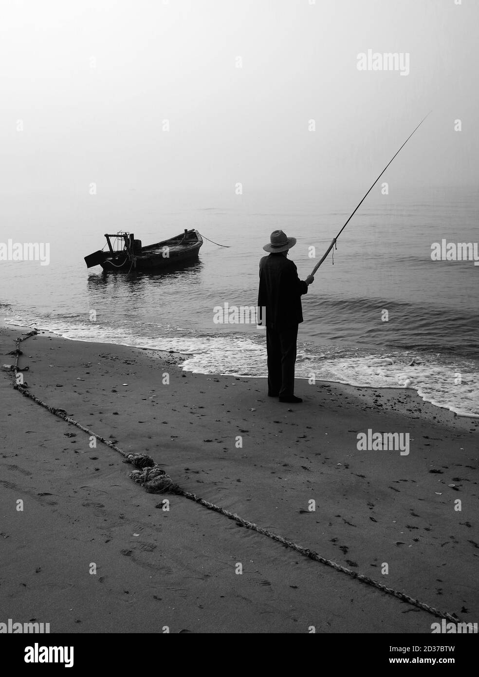 Chinesischer Fischer mit Angelrute und altem Boot Stockfoto