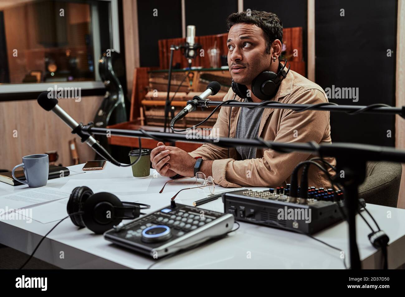 Portrait von jungen männlichen Radio-Host suchen fokussiert, während immer Bereit für die Moderation einer Live-Show im Studio Stockfoto