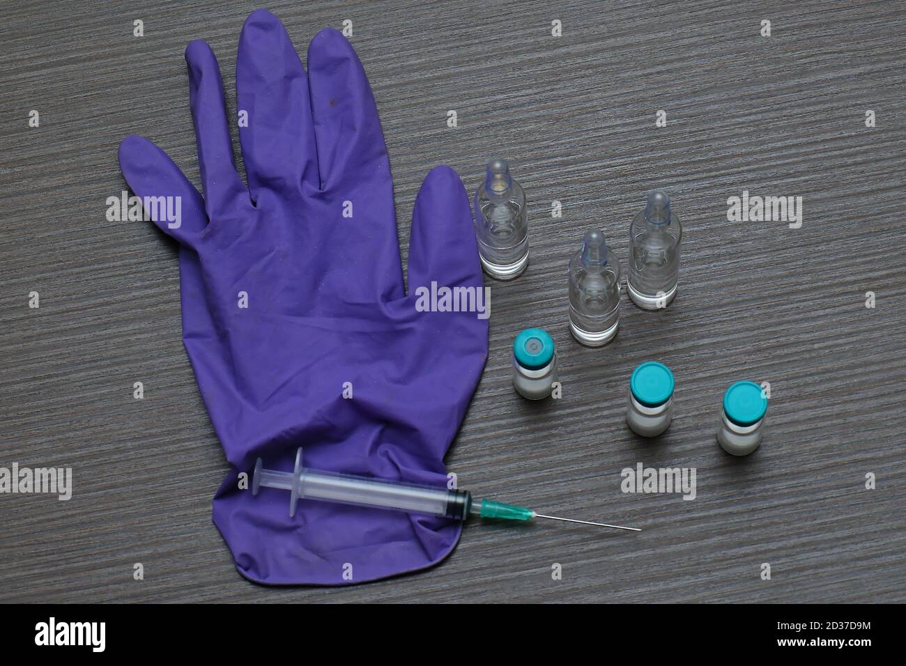 Impffläschchen mit Nadelinjektion und medizinischem Handschuh Stockfoto