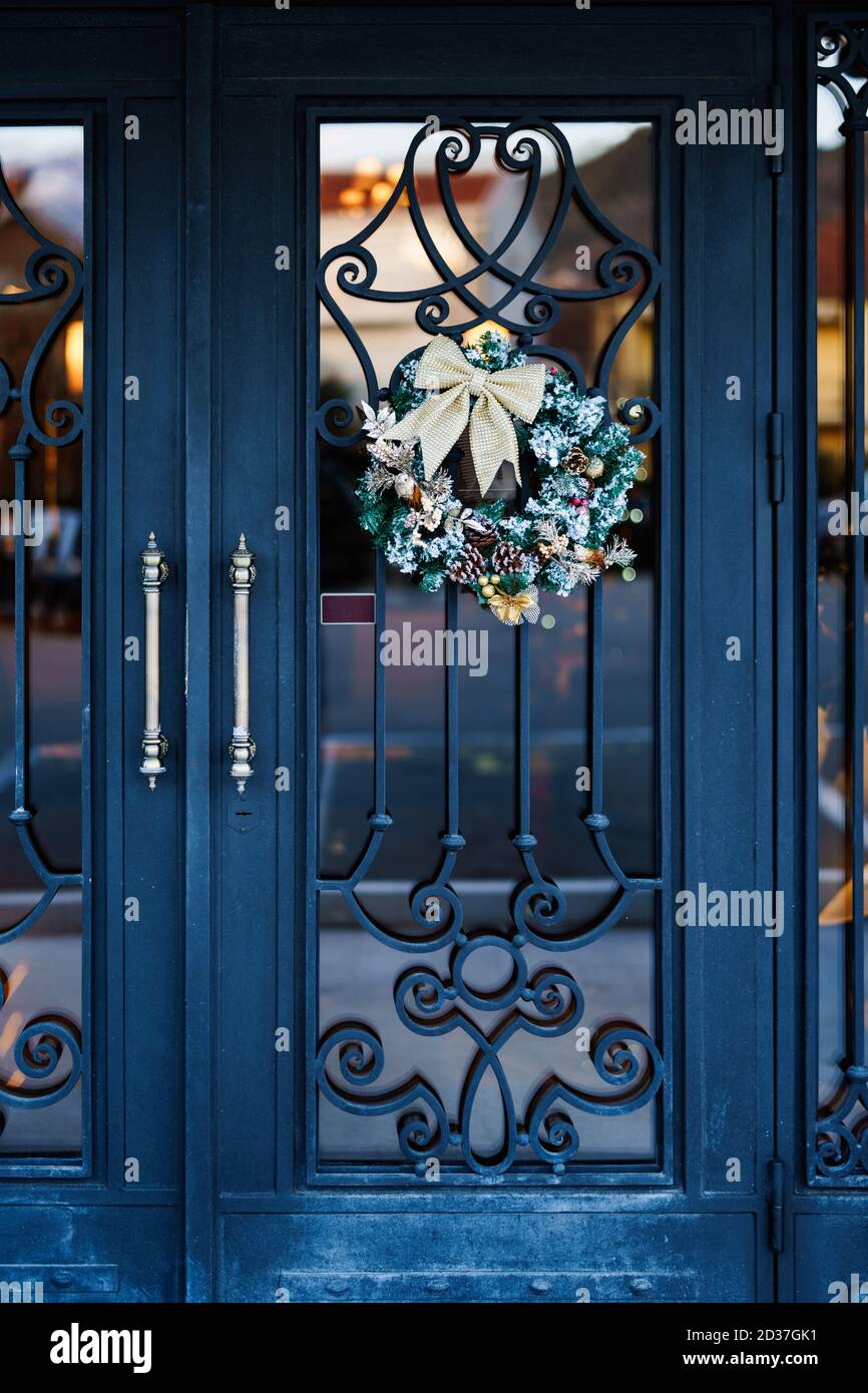 Schöner Weihnachtskranz an der Tür mit schmiedeeisernem Muster. Stockfoto