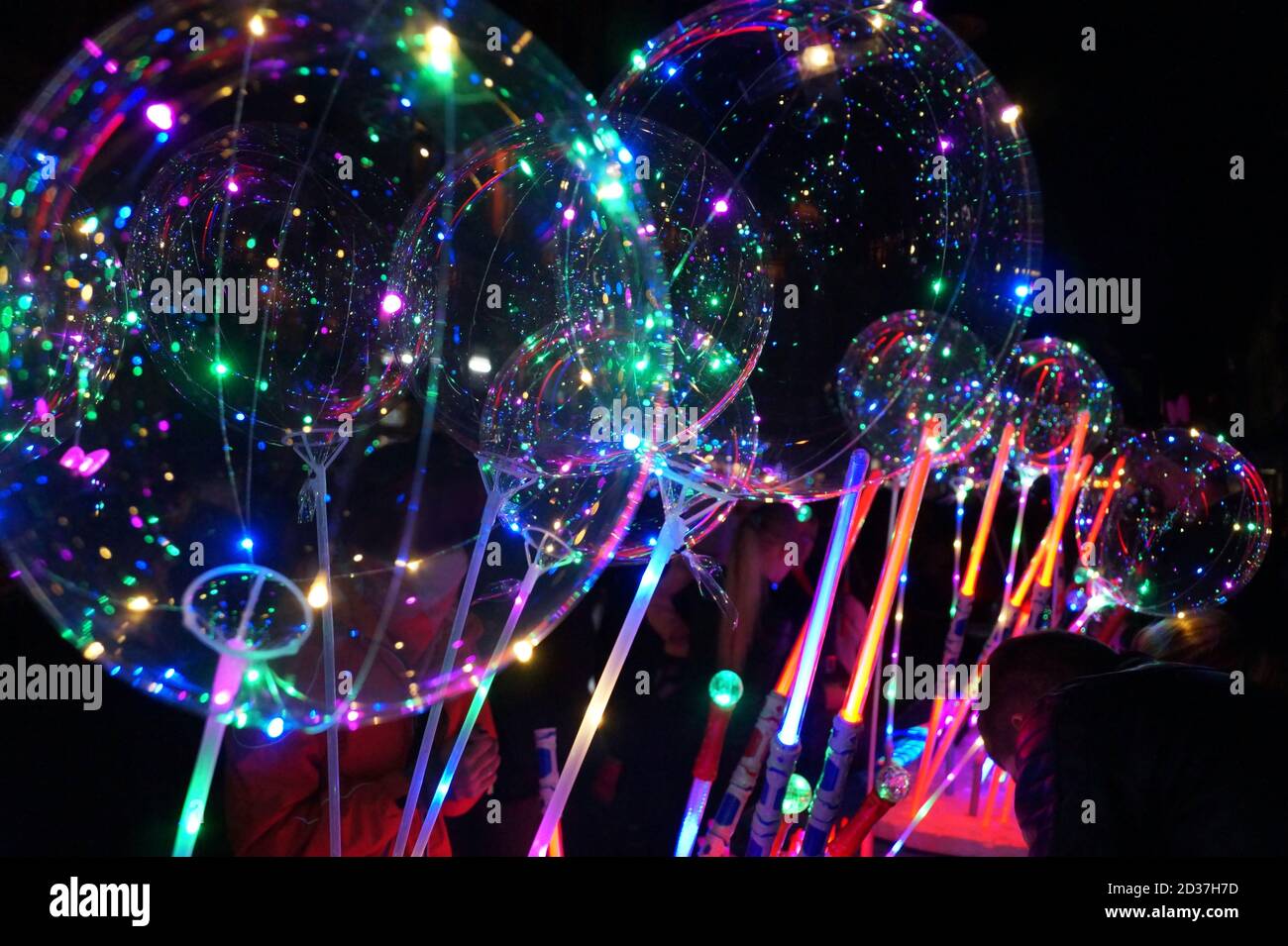 Nacht. Ein Stand, der leuchtende Spielzeuge verkauft: Ballons und Schwerter Stockfoto