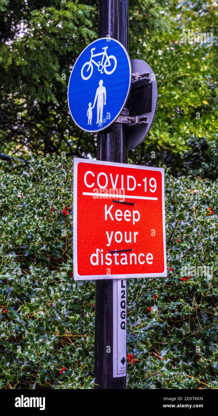 Covid-19 Halten Sie Ihr Wegweiser auf einem gemeinsam genutzten Rad- und Fußwanderweg. Coronavirus Halten Sie Ihr Entfernungszeichen. Stockfoto