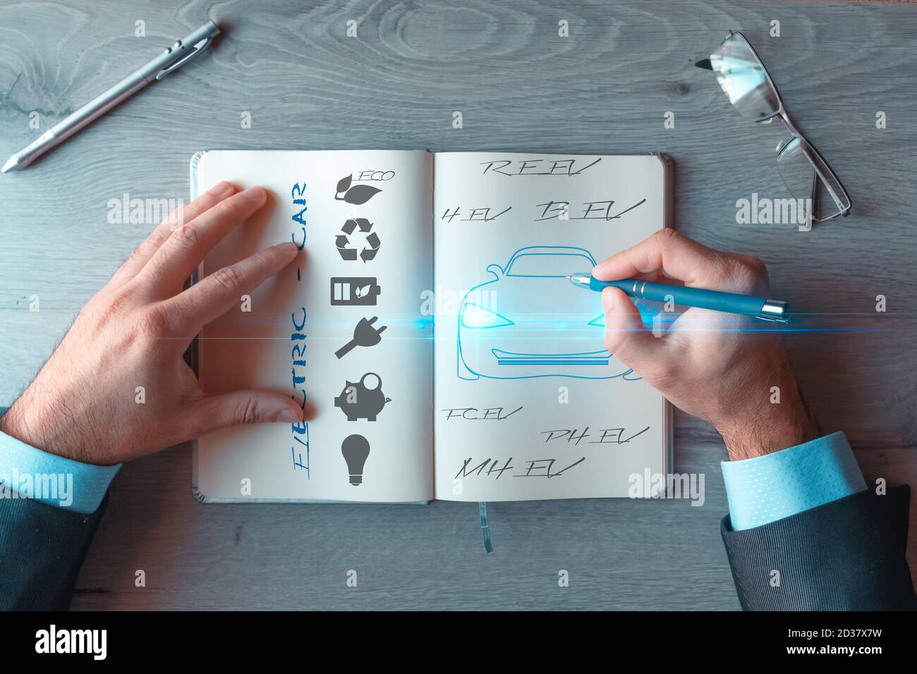 Hände eines Geschäftsmannes, der eine Idee des Elektroautos in einem Notizbuch schreibt. Geschäftskonzept. Technologie der Zukunft Stockfoto