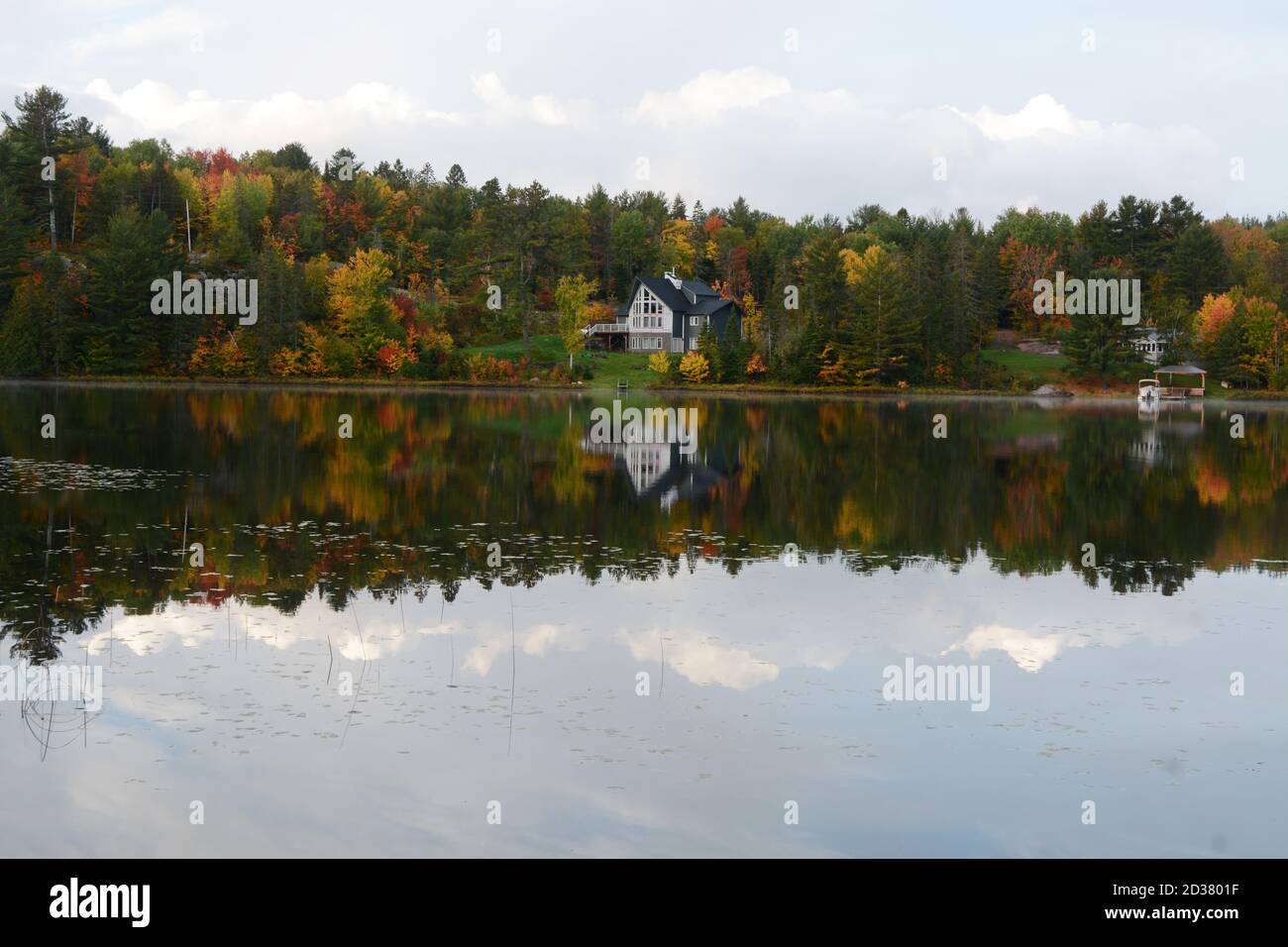 Eine Spiegelung der Häuser, Hütten und der Wald im French River im Herbst gesehen, in French River, Zentral-Ontario, Kanada. Stockfoto