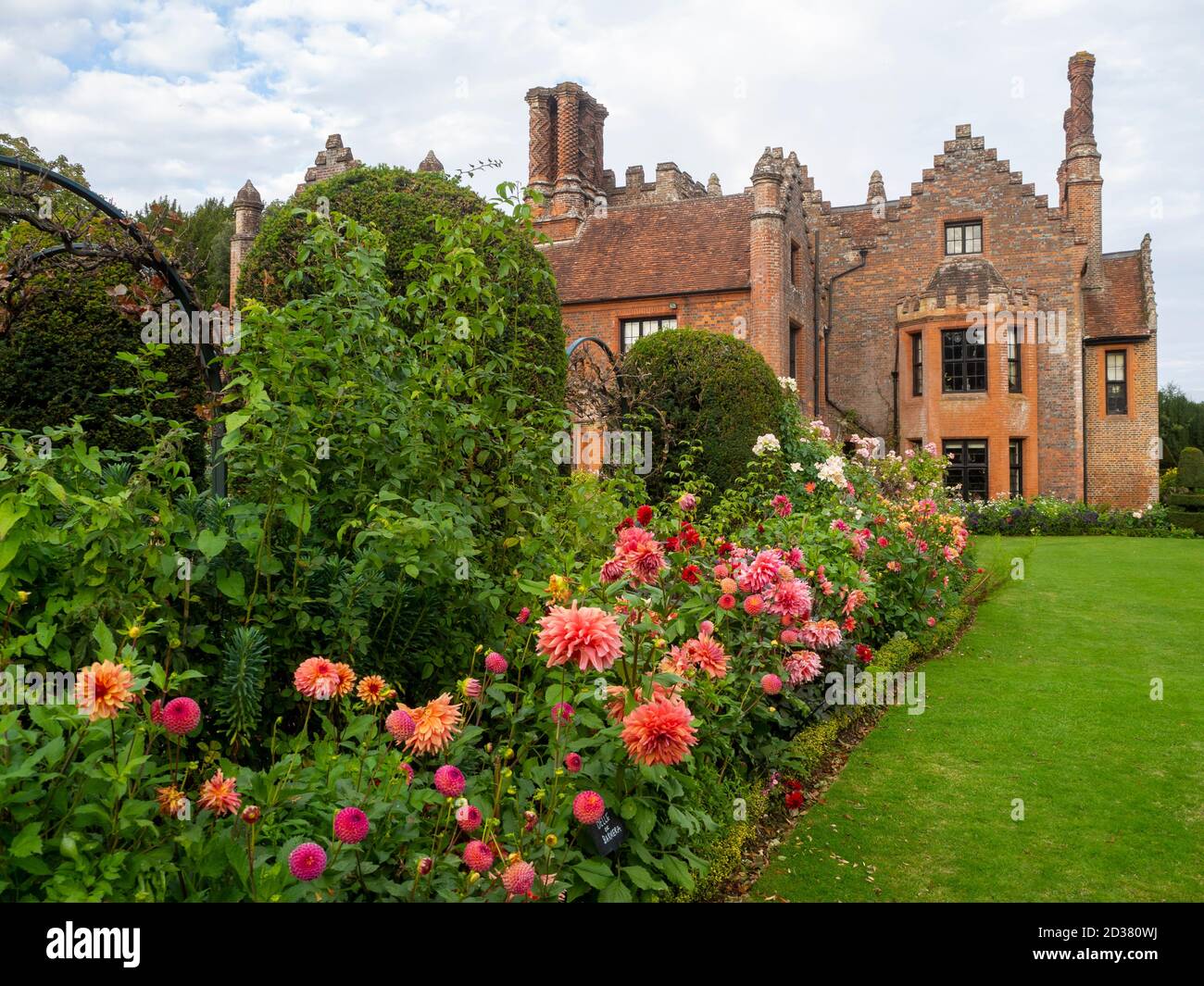 Chenies Manor Gärten im September. Atemberaubende Pfirsich- und lachsrosa Dahlia-Ausstellung im Tudor Manor als Kulisse an einem schönen Nachmittag im Spätsommer. Stockfoto