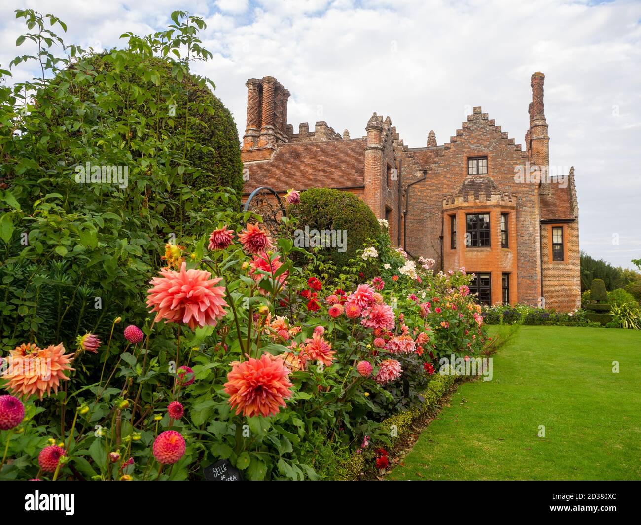 Chenies Manor Gärten im September. Atemberaubende Pfirsich- und lachsrosa Dahlia-Ausstellung im Tudor Manor als Kulisse an einem schönen Nachmittag im Spätsommer. Stockfoto