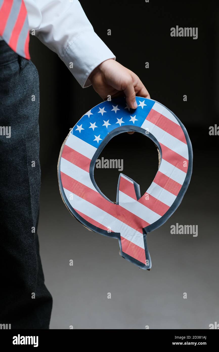 QAnon Verschwörung Bewegung Konzept. Hand des Kindes mit Q-Brief mit amerikanischer Flagge. Konzeptbild. Selektiver Fokus. Stockfoto