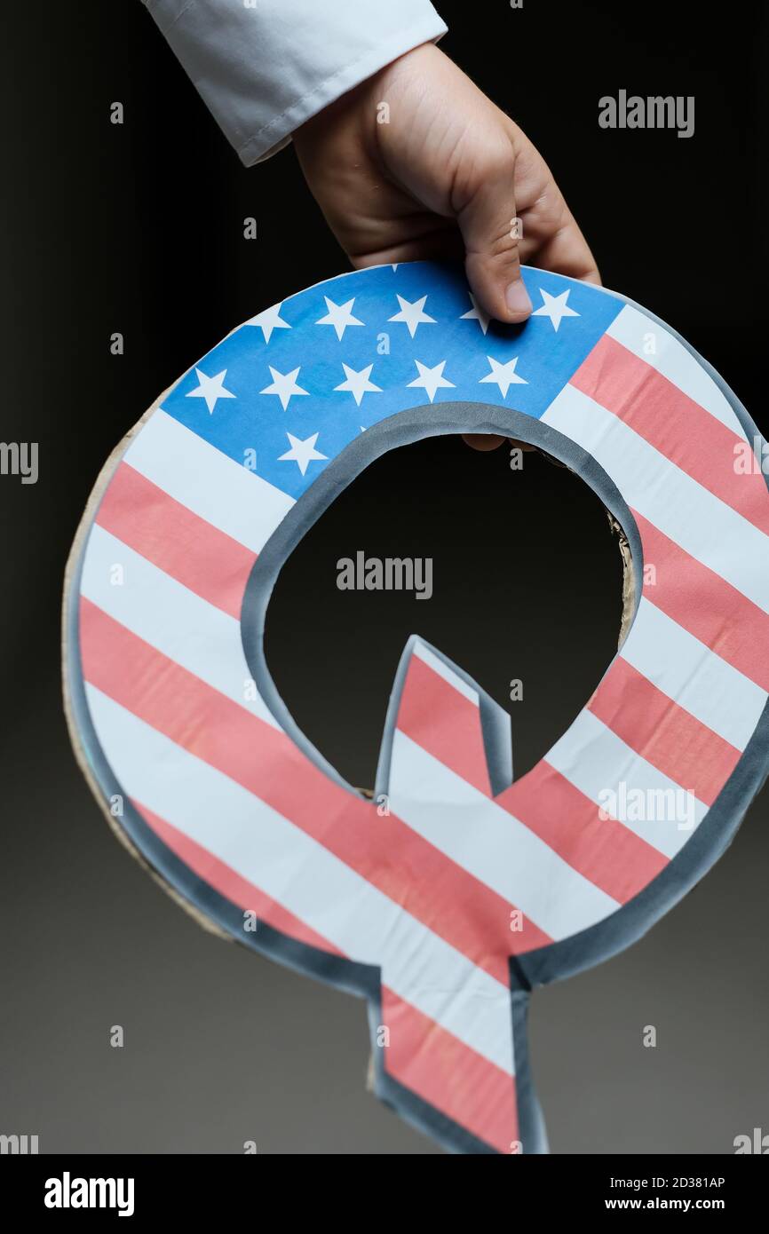 QAnon Verschwörung Bewegung Konzept. Hand des Kindes mit Q-Brief mit amerikanischer Flagge. Konzeptbild. Selektiver Fokus. Stockfoto