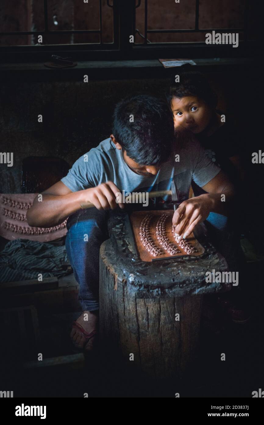 Dalit arbeitete im Dunkeln mit seiner Tochter, die ihn beobachtete. Eine Gruppe junger Menschen arbeitet in einem kleinen Gebäude in einem Vorort von Kathmandu, Nepal. Stockfoto