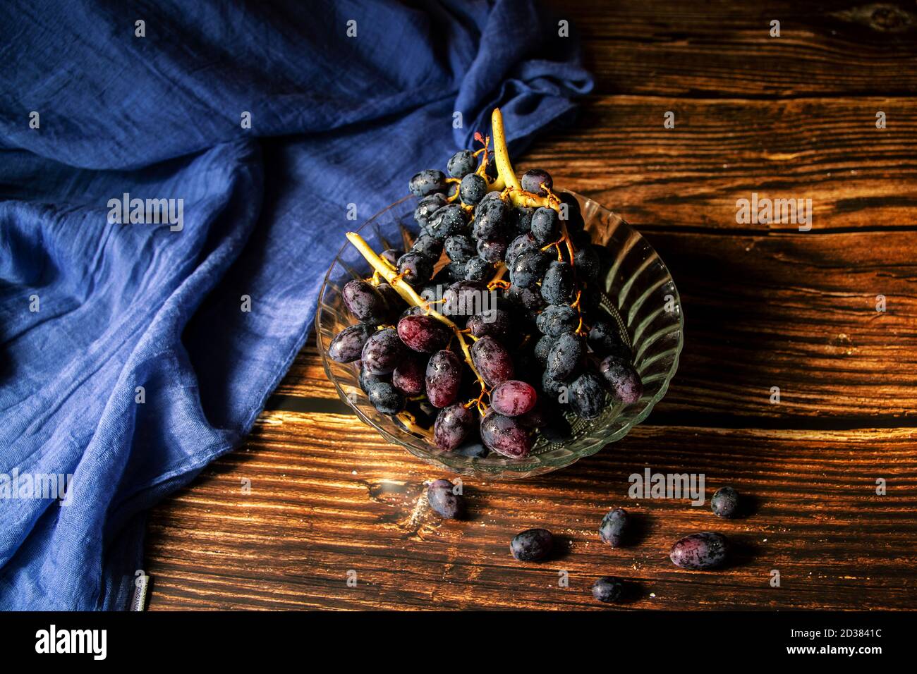 Schwarze Trauben in einer Glasschale auf einem Holztisch Stockfoto Schwarze Trauben in einer Glasschale auf einem Holztisch Stockfoto