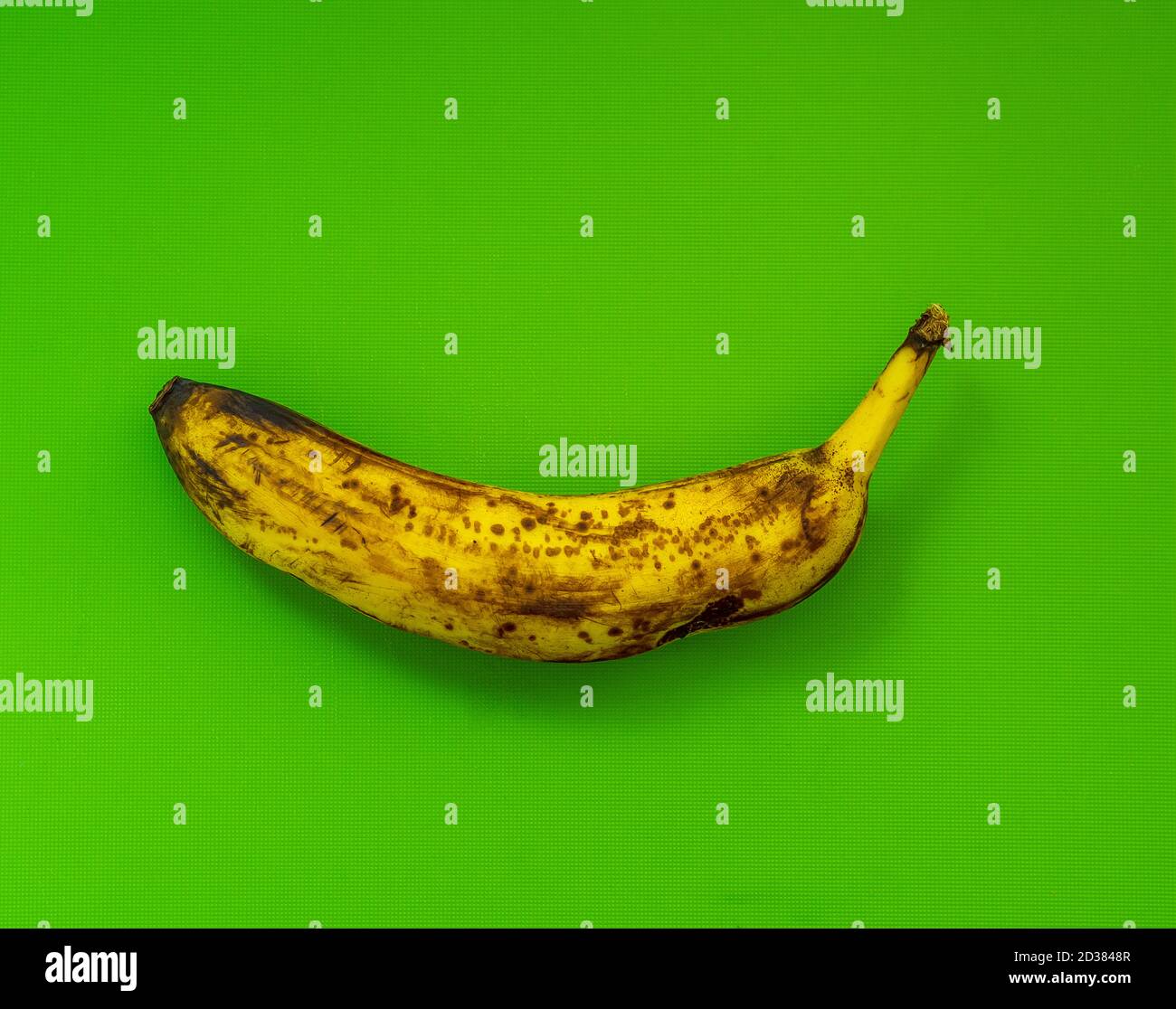 Einzelne überreife Banane mit grünem Hintergrund Stockfoto