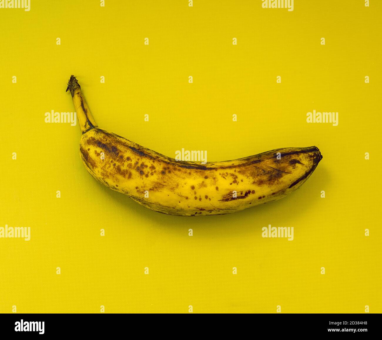Einzelne überreife Banane mit gelbem Hintergrund Stockfoto