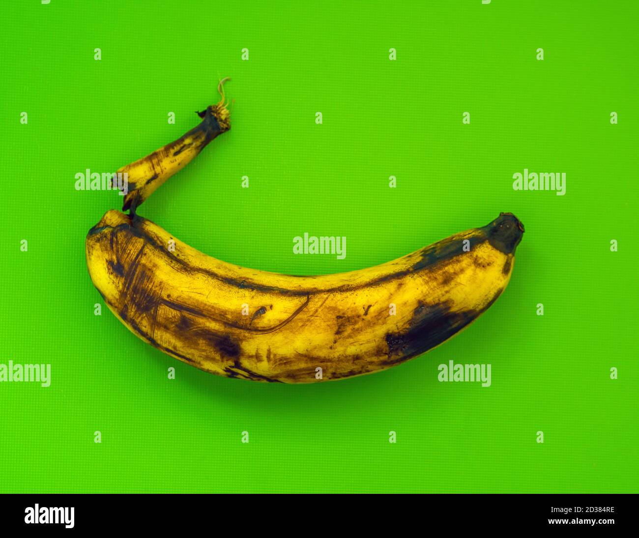 Einzelne überreife Banane mit grünem Hintergrund Stockfoto