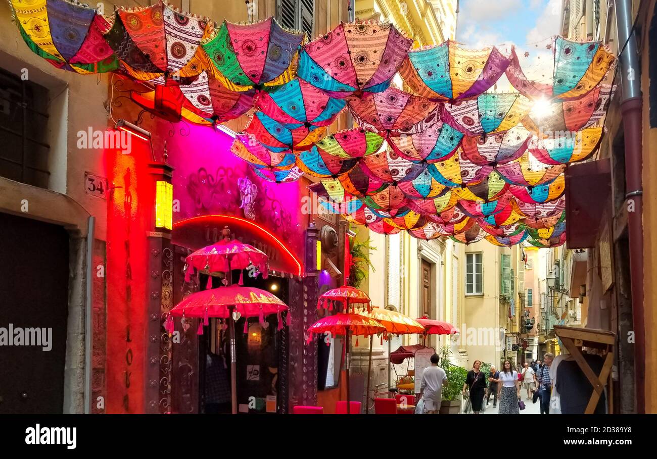 Touristen passieren unter einem bunten Sonnenschirm vor einem Geschäft in der Altstadt von Nizza Frankreich, an der Cote d'Azur. Stockfoto