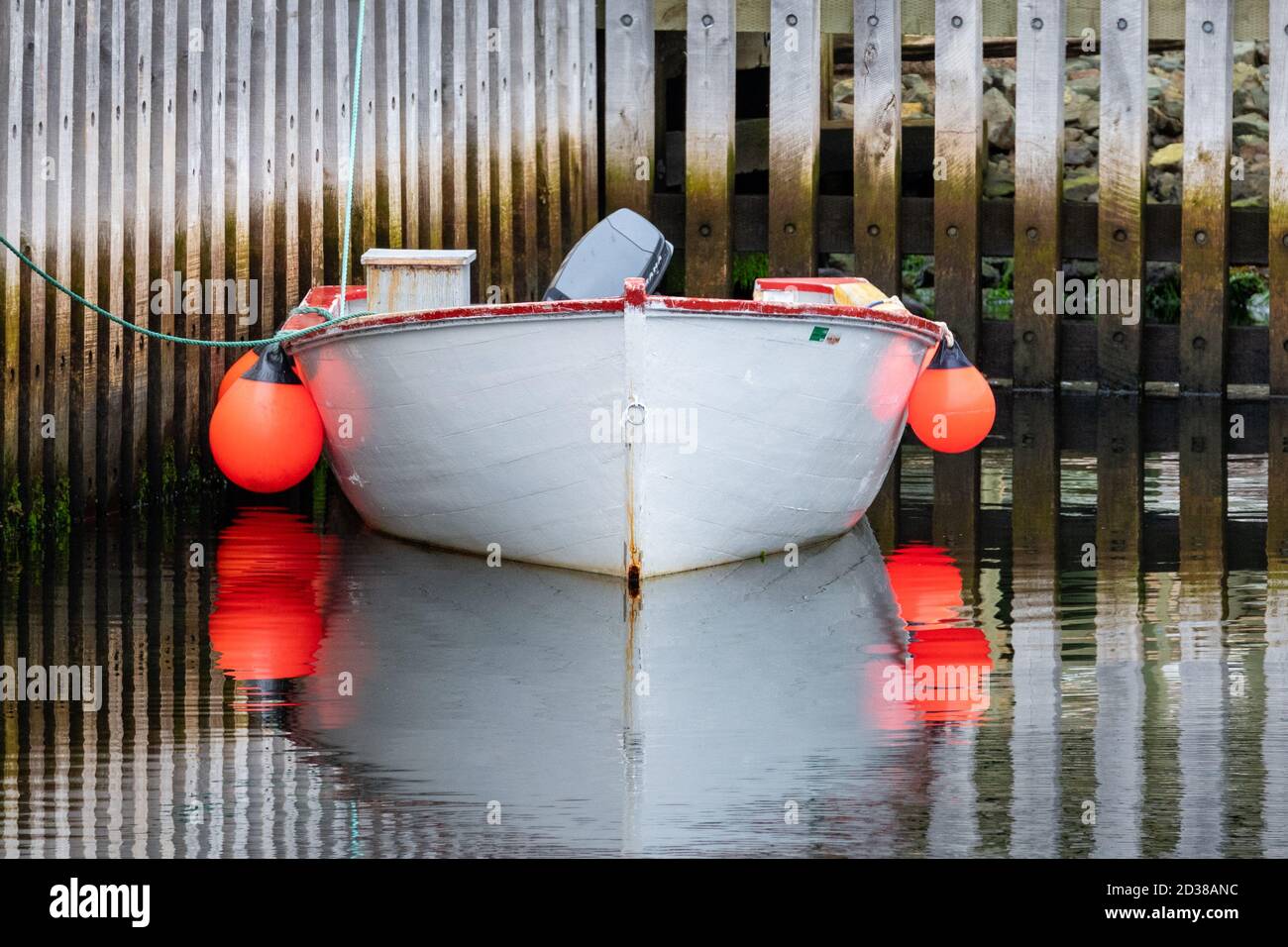 St. John's, Neufundland / Kanada Oktober 2020: Ein weißes Fischerboot aus Holz, das mit mehreren Bojen, Außenbordmotor und roten Zierleisten um die Spitze festgemacht ist. Stockfoto