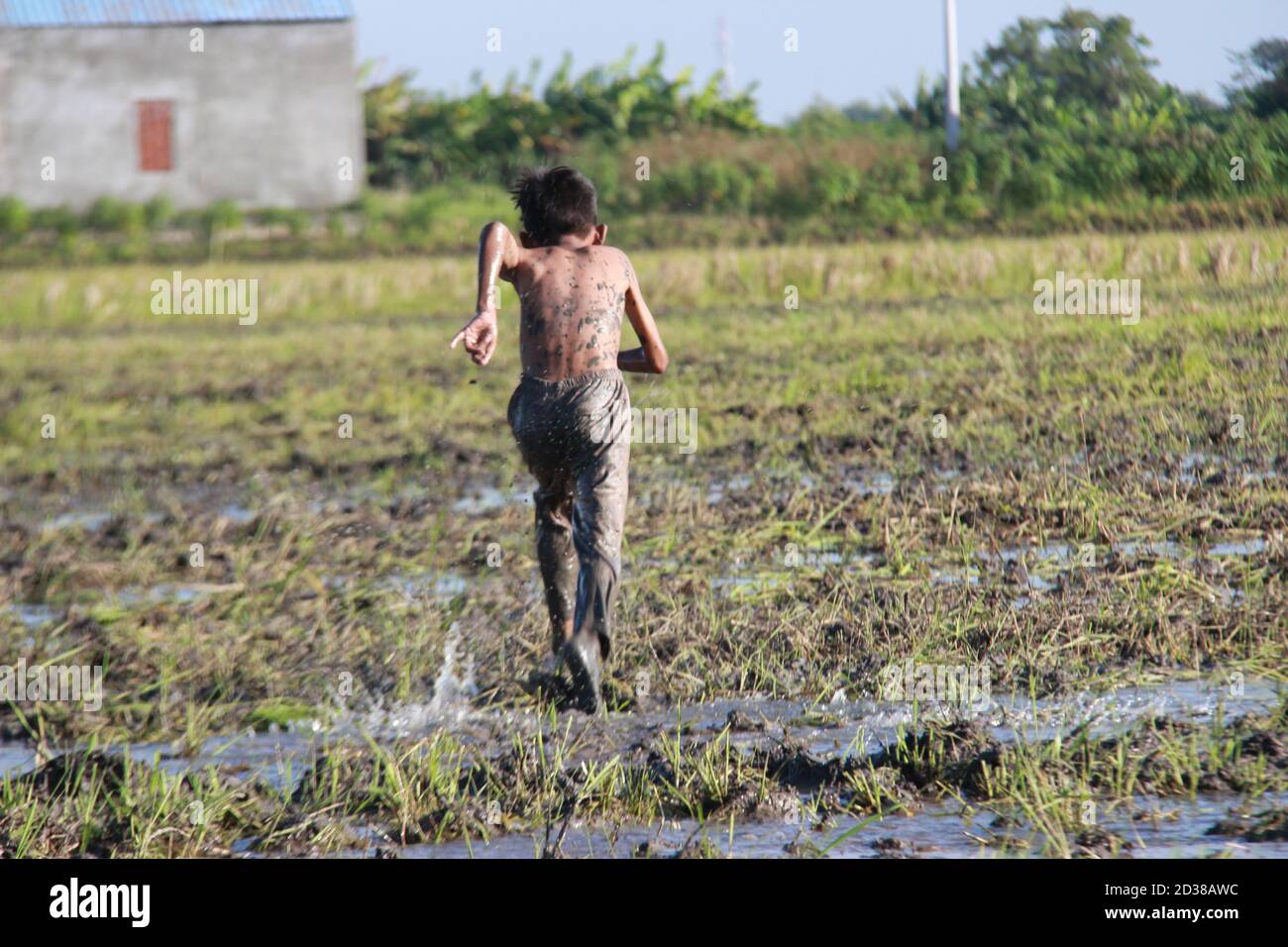 Asiatische Jugendliche laufen durch den Schlamm der Reisfelder. Aktiv spielen in der schmutzigen Natur. Dorf Kinder Glück Aktivitäten während im Urlaub Stockfoto