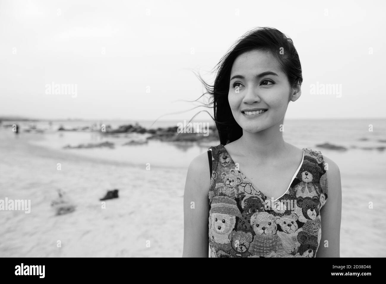 In der Nähe der Jugendlichen glücklich schöne asiatische Frau lächelnd, während am öffentlichen Strand von Hua Hin in Thailand denken Stockfoto