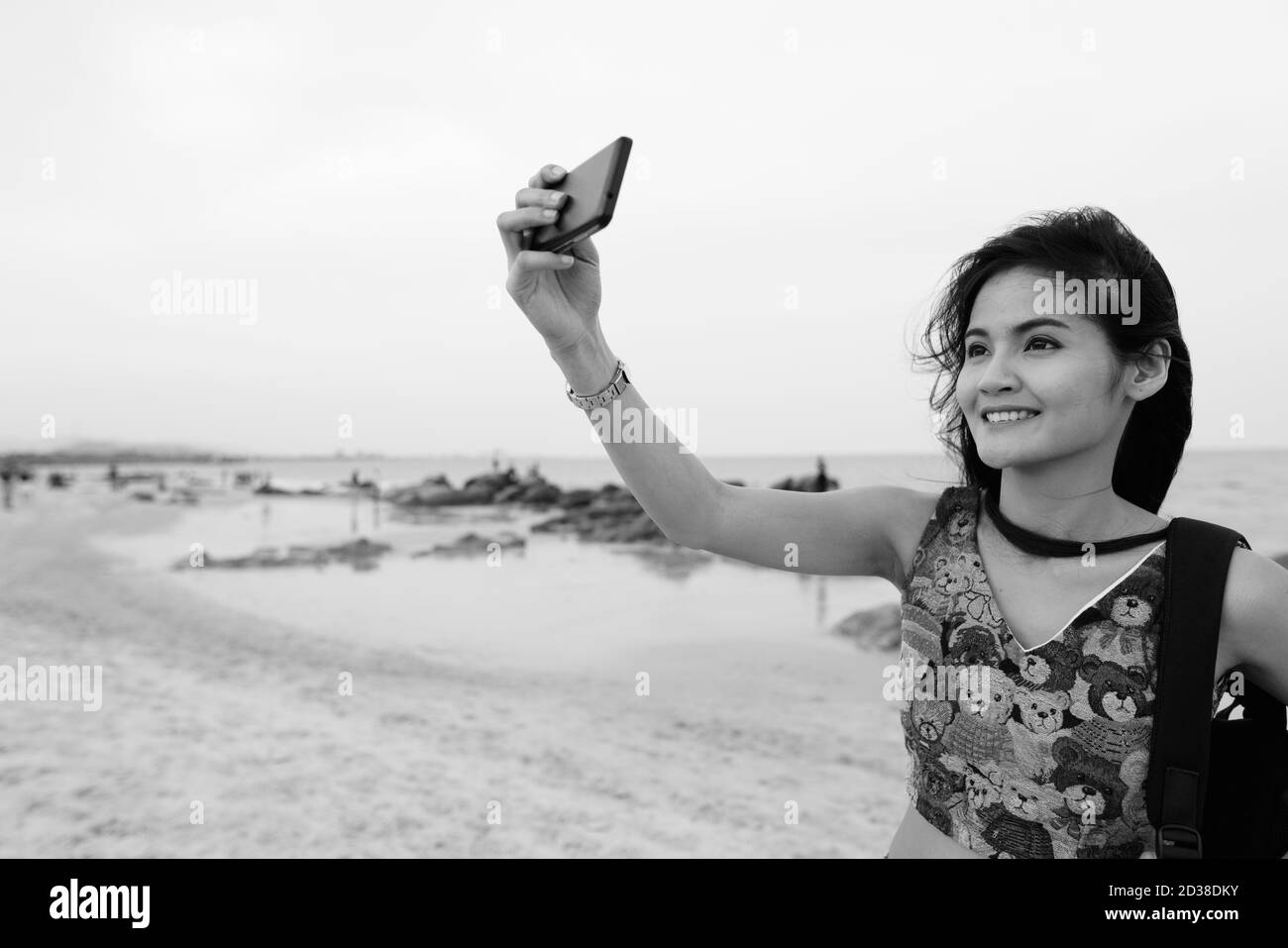 Junge asiatische Frau glücklich lächelnd während der Einnahme von selfie Bild mit Handy am öffentlichen Strand von Hua Hin in Thailand Stockfoto