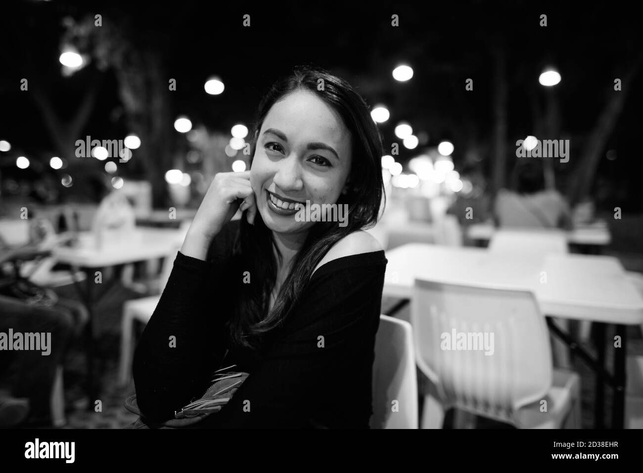 Junge glücklich schöne asiatische Frau lächelnd, während auf dem Nachtmarkt von Hua Hin in Thailand sitzen Stockfoto