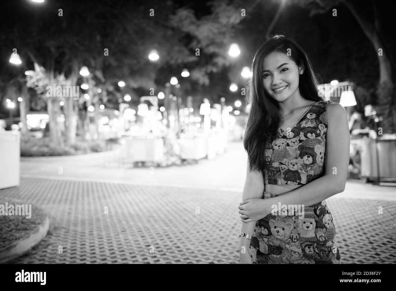 Junge glücklich schöne asiatische Frau gegen einen malerischen Blick auf den Nachtmarkt in Hua Hin Thailand lächelnd Stockfoto