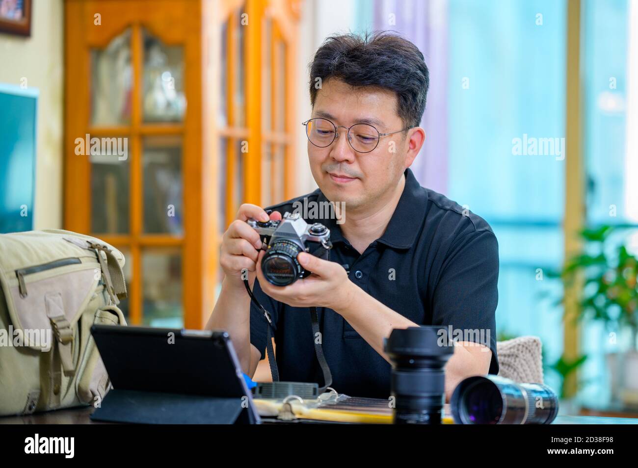 Ein asiatischer Mann mittleren Alters, dessen Hobby 35mm/135mm Film SLR-Kamera ist. Stockfoto