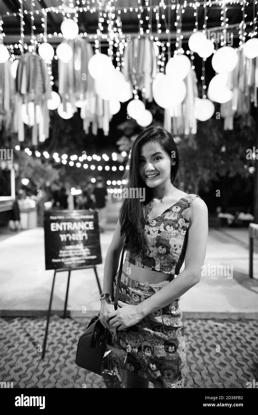 Junge glücklich schöne asiatische Frau lächelnd und stehend an der Eintritt der offenen Live-Band in den Nachtmarkt Stockfoto