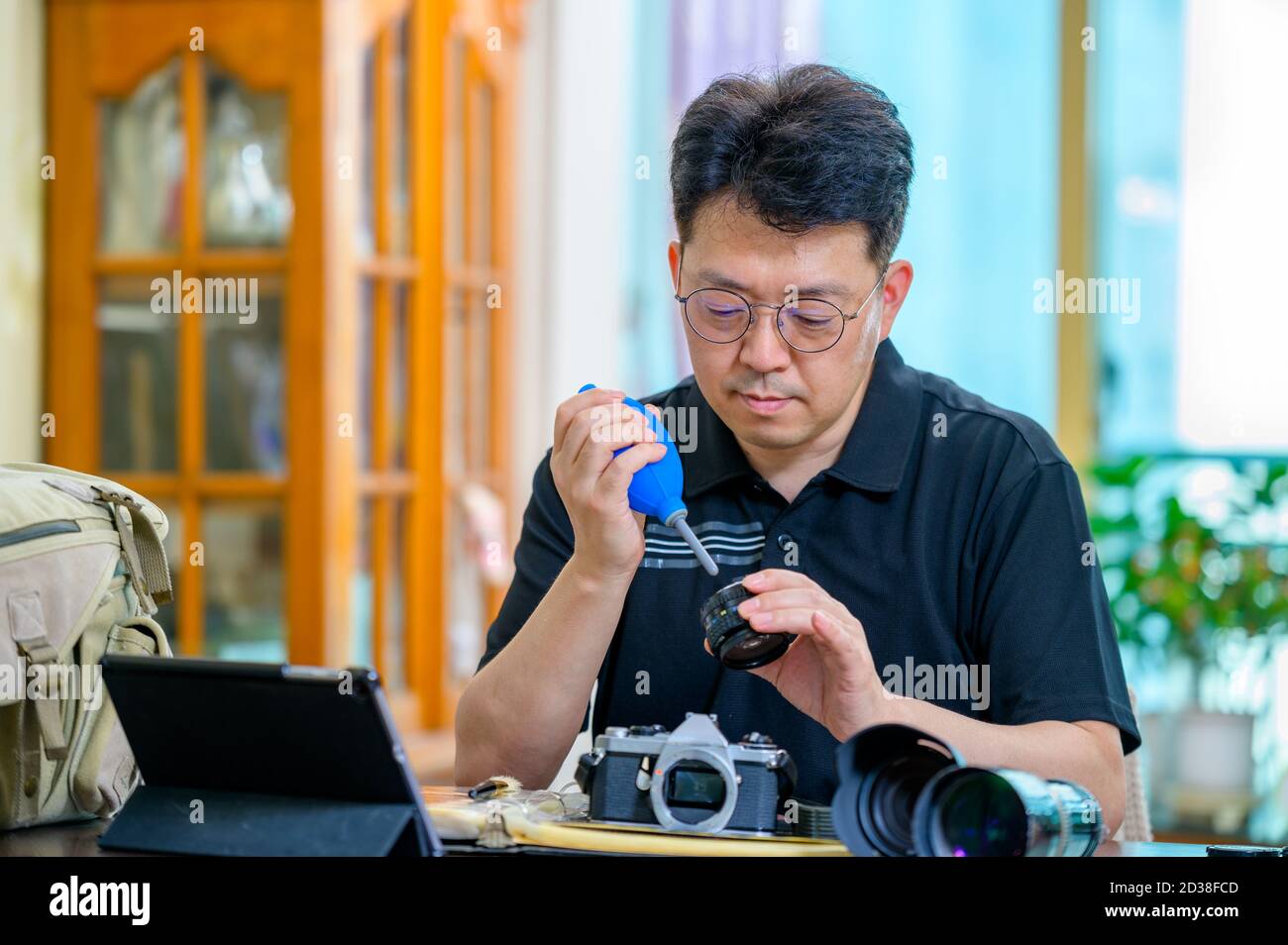 Ein asiatischer Mann mittleren Alters, dessen Hobby 35mm/135mm Film SLR-Kamera ist. Stockfoto