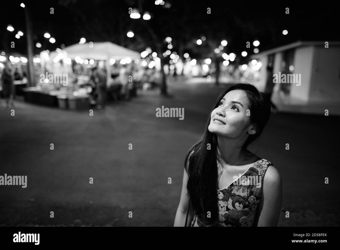 Junge glücklich schöne asiatische Frau denken und schauen gegen Blick auf den Nachtmarkt Stockfoto