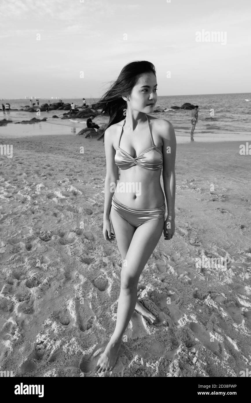 Junge schöne asiatische Frau denken, während am Strand stehen Stockfoto