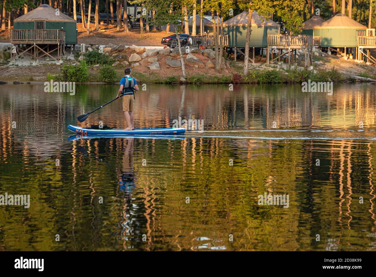 Stand Up Paddlebarder paddeln vorbei an Campingplätzen Jurten im Stone Mountain Park in Atlanta, Georgia. (USA) Stockfoto