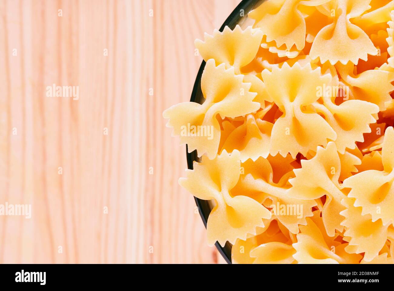 Trockene Pasta Farfalle in Glasschale auf Holztisch, Fliege Pasta oder Schmetterling Pasta mit zwei gerafften Kanten und die Mitte zusammengeknickt Stockfoto