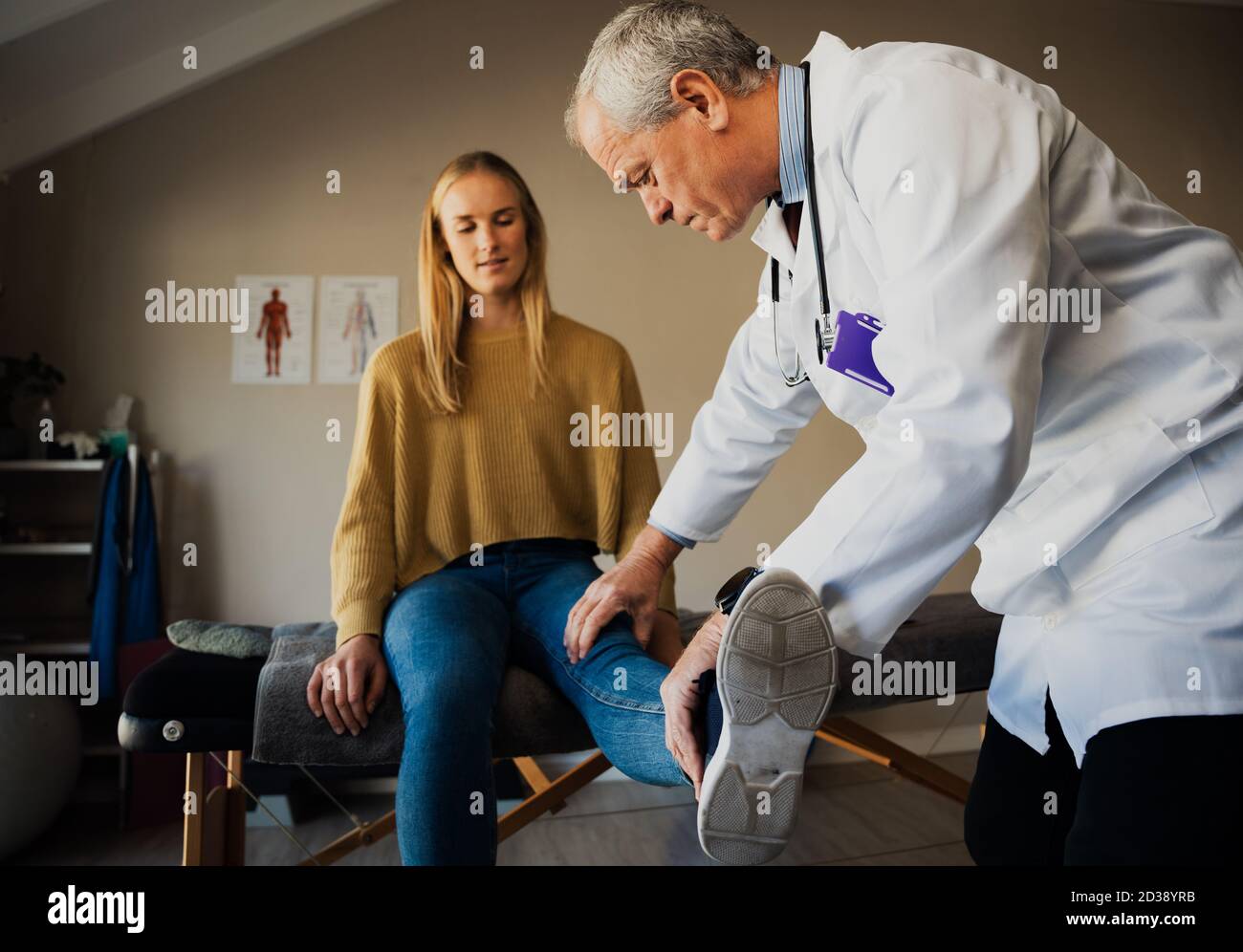 Männlich Arzt im weißen Mantel Behandlung von weiblichen Patienten verletzt Knie Im Rehabilitationszentrum Stockfoto
