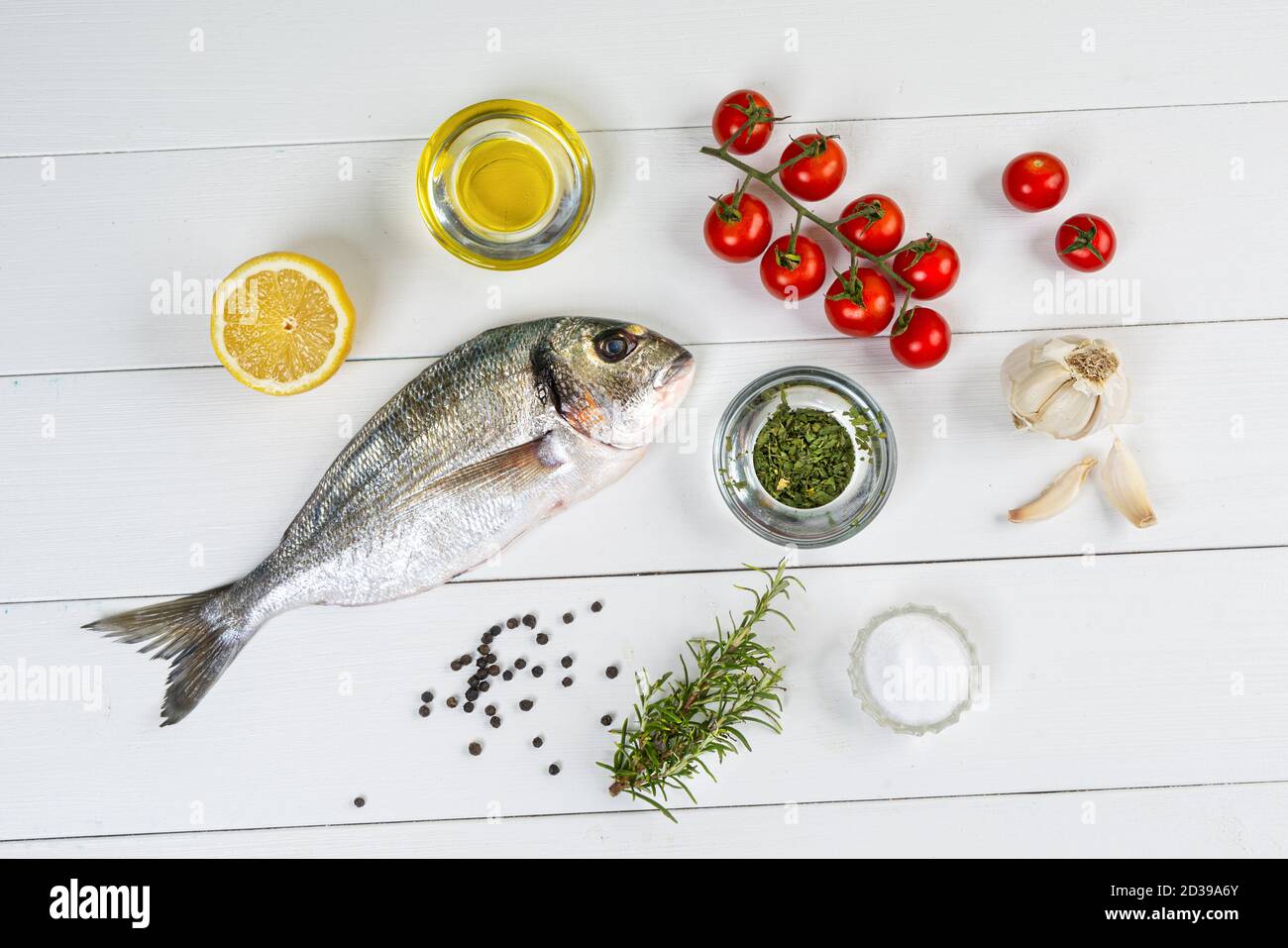 Eine Seebrasse und mit Produkten für die Herstellung von Ein Rezept auf einem weißen Holztisch Stockfoto