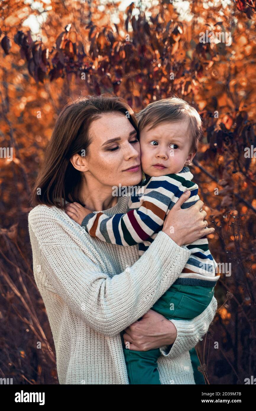 Netter kleiner Junge in den Armen seiner Mutter. Frau zu Hause trägt ihren neugeborenen Sohn. Stockfoto