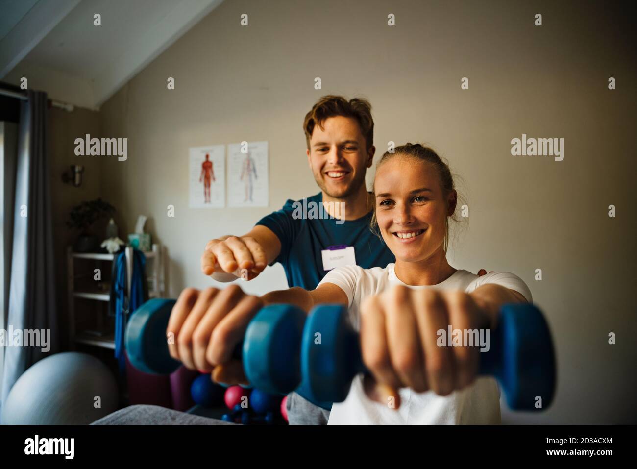 Männliche Physiotherapeut Instructing kaukasischen weiblichen Patienten richtige Übungsform mit Kurzhanteln Stockfoto