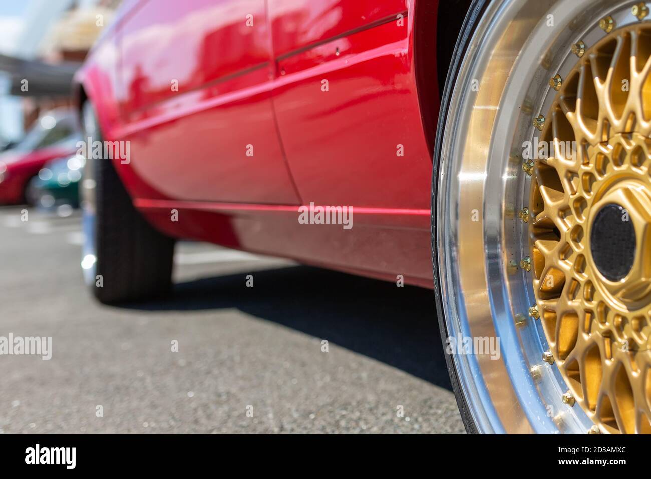Radauto. Schönes goldenes Rad auf einem Hintergrund eines roten Sportwagens Stockfoto