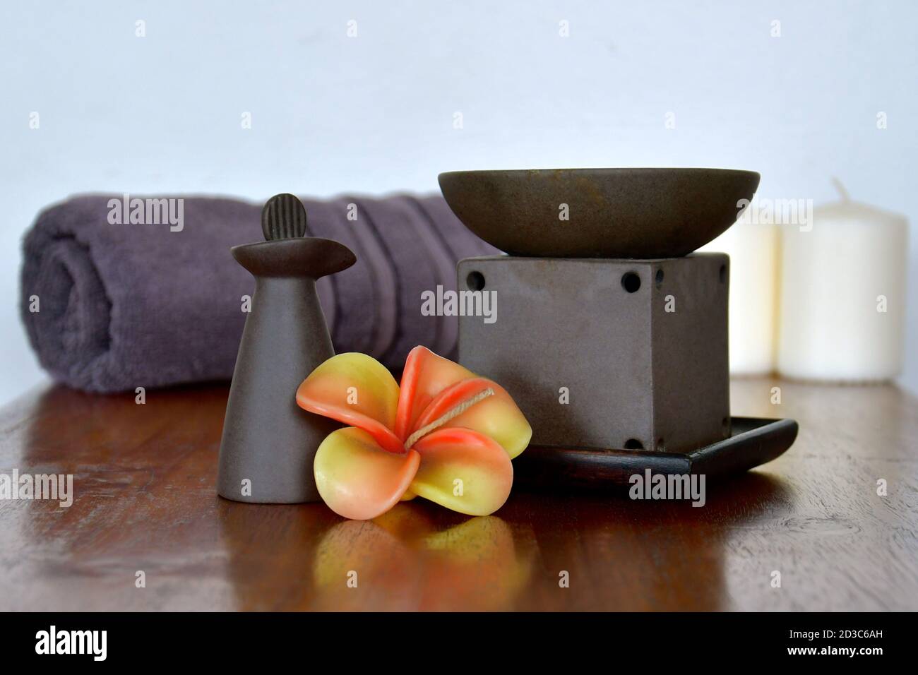 Aromatherapie-Ölbrenner und Tonflasche in luxuriöser Spa-Umgebung mit Frangipani-Blumen. Stockfoto