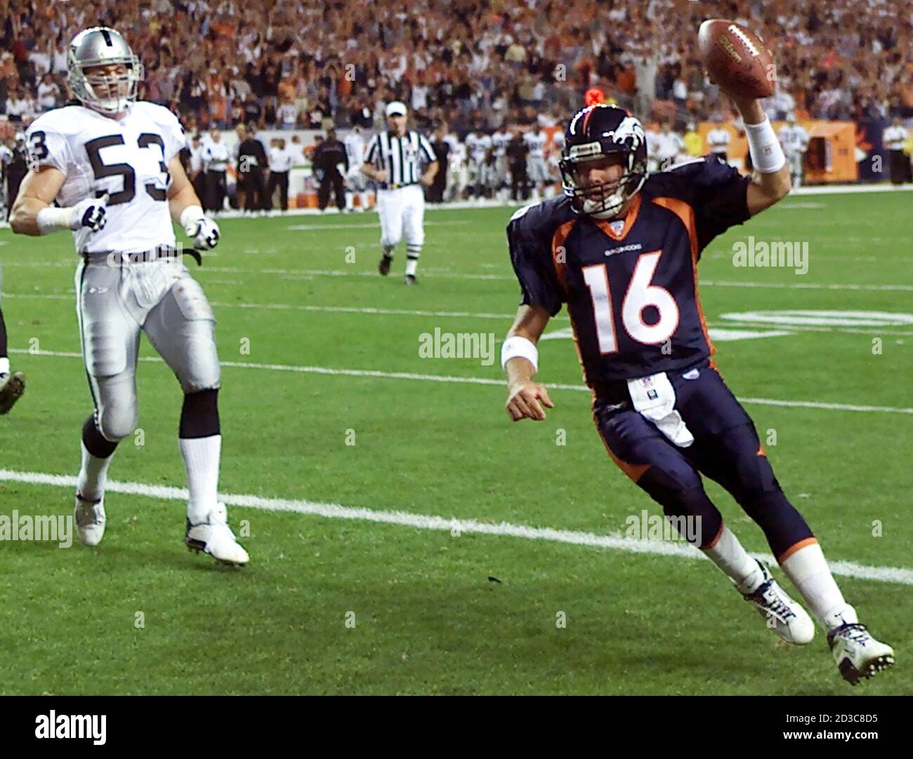 Denver Broncos Quarterback Jake Plummer läuft für eine sechs-Yard-Touchdown mit Oakland Raiders Linienhalter Bill Romanowski in Verfolgung im ersten Quartal in Denver 22. September 2003. Plummer feierte sein reguläres Saisondebüt als Broncos neuer Startquarter. REUTERS/Gary C. Caskey Stockfoto